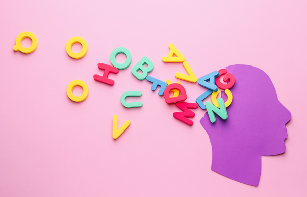 Carta testa umana con lettere su sfondo a colori. Concetto di dislessia - Foto, immagini