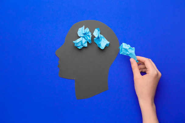 Weibliche Hand, menschlicher Kopf und zerknüllte Papierstücke auf farbigem Hintergrund. Konzept der Demenz - Foto, Bild