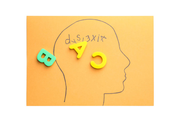 Papel con cabeza humana dibujada, palabra DYSLEXIA y letras sobre fondo blanco
 - Foto, imagen