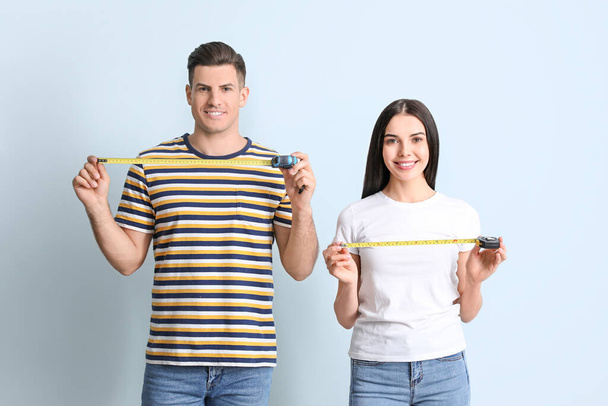 Paar mit Maßbändern auf farbigem Hintergrund - Foto, Bild