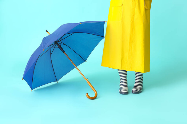 Woman in raincoat and with umbrella on color background - Фото, зображення