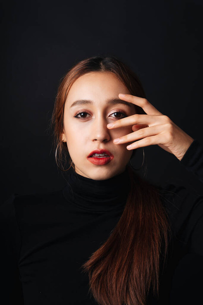 Close up portret van vrij mooie jonge vrouw dragen zwarte trui isoleren over donkere achtergrond. - Foto, afbeelding