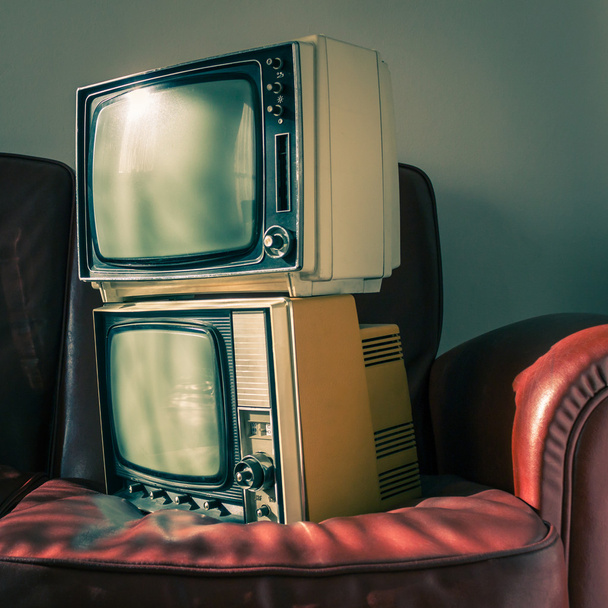 Two vintage televisions on red couch - Фото, зображення
