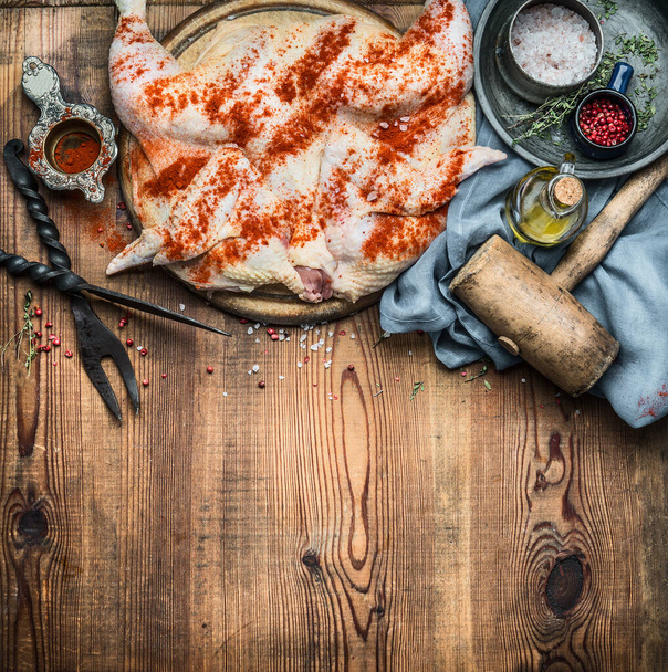 Whole chicken flattened out with condiment and kitchen tools on wooden rustic background, cooking preparation , top view. Chicken Tabaka traditional Georgian dish , Caucasian cuisine - Fotografie, Obrázek