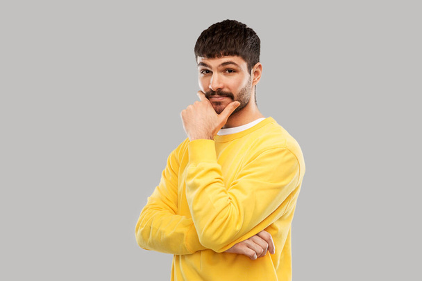 thinking young man in yellow sweatshirt - Zdjęcie, obraz
