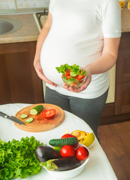 A pregnant woman eats vegetables and fruits. Selective focus. Food. - Photo, image