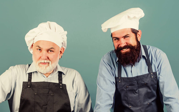 Cafe workers. Restaurant kitchen. Culinary industry. Restaurant staff. Father and son culinary hobby. Family restaurant. Mature bearded men professional restaurant cooks. Chef men wear aprons - Photo, Image