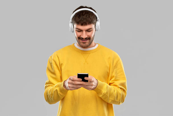 smiling young man with headphones and smartphone - Fotografie, Obrázek