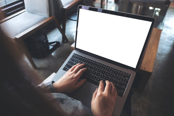 Вид зверху макет зображення ділової жінки, що використовує і друкує на ноутбуці з порожнім білим екраном робочого столу, сидячи на дерев'яному стільці в кафе
 - Фото, зображення