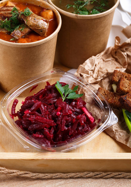 Borscht tradicional ucraniano y caldo de verduras en vasos de papel, ensalada de remolacha en tazón de vidrio
 - Foto, Imagen
