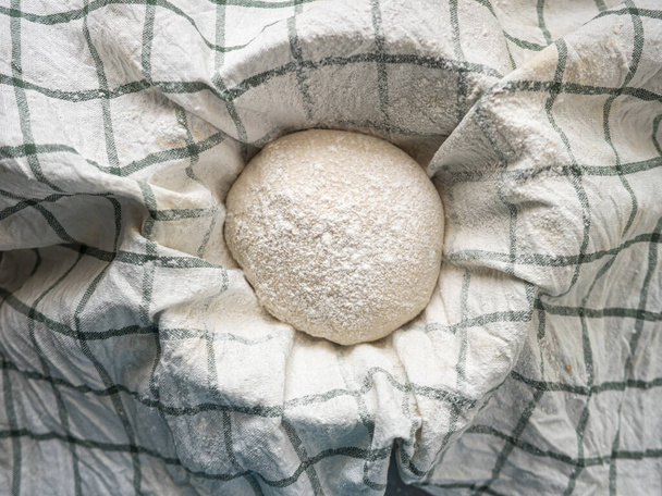 Traditional home made sourdough bread proofing in basket covered with tea towel in kitchen before bake - Photo, Image