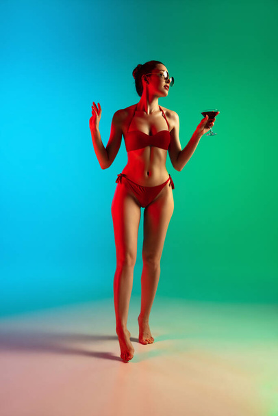 Fashion portrait of seductive girl in stylish swimwear posing on a bright gradient background. Summertime, beach season - Фото, изображение