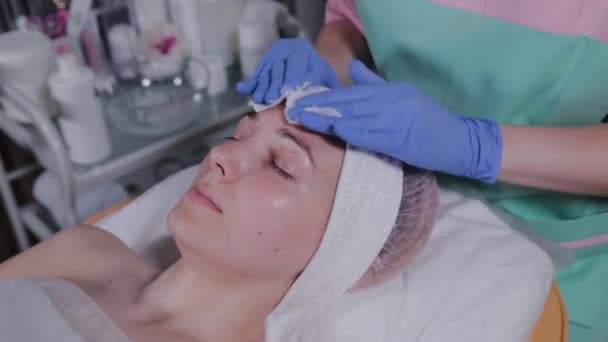 Profesyonel güzellik uzmanı bir kadının yüzünü pamukla siliyor.. - Video, Çekim