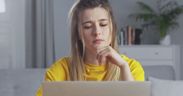 Concerned sad woman responing to messages in a chat on social networks, looking at the computer screen in thought. Disappointed girl working at the laptop. - Filmmaterial, Video