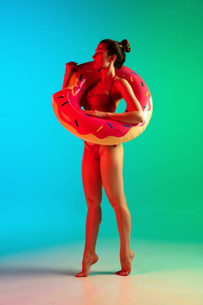 Fashion portrait of seductive girl in stylish swimwear posing on a bright gradient background. Summertime, beach season - Фото, изображение