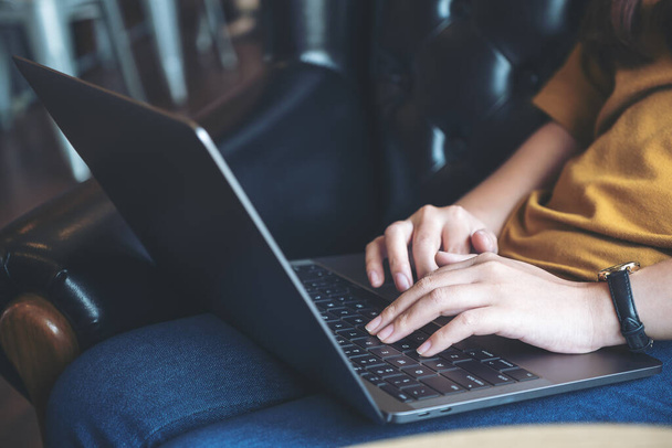 Detailní záběr ženských rukou, jak pracují a píší na klávesnici notebooku, zatímco sedí na pohovce - Fotografie, Obrázek