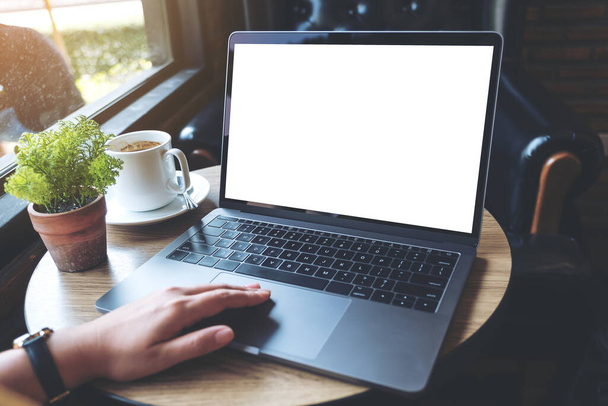 Образец изображения руки, использующей и касающейся ноутбука с белым экраном рабочего стола и чашкой кофе на деревянном столе в кафе
 - Фото, изображение
