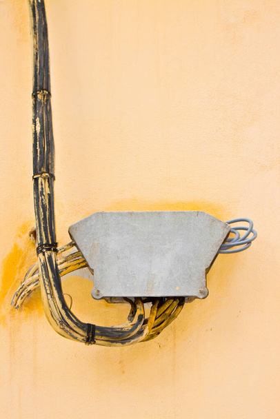 Καλώδια ηλεκτρικού ρεύματος και τηλεφώνου στερεωμένα σε τοίχο από γύψο με κιβώτιο σύνδεσης προστασίας - Φωτογραφία, εικόνα
