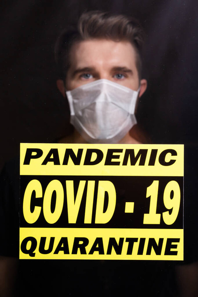 Koronavirus, karanténa, covid-19 a pandemická koncepce. Smutný a nemocný muž s virem korony se dívá oknem. Zůstaň doma.. - Fotografie, Obrázek