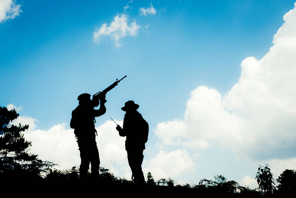 Силуетне зображення двох озброєних солдатів з фоном блакитного неба
 - Фото, зображення