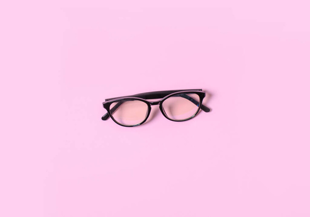 Комп'ютерні окуляри лежать в центрі на рожевому фоні
. - Фото, зображення