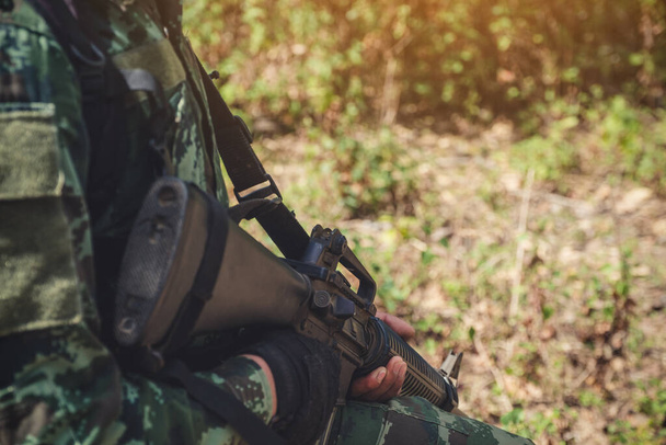 Detailní záběr ozbrojeného vojáka držícího zbraň na bitevním poli - Fotografie, Obrázek