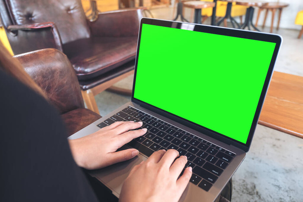 カフェで木製のテーブルの上に空白の緑のデスクトップ画面とノートパソコンを使用して入力するビジネスマンのモックアップイメージ - 写真・画像