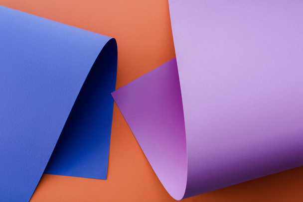 blue and violet colorful paper on orange background - Foto, afbeelding