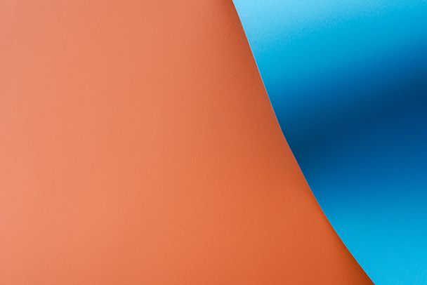 μπλε πολύχρωμο κυματιστό χαρτί σε πορτοκαλί φόντο - Φωτογραφία, εικόνα
