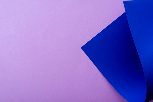 curved blue paper on violet background - Foto, Imagem