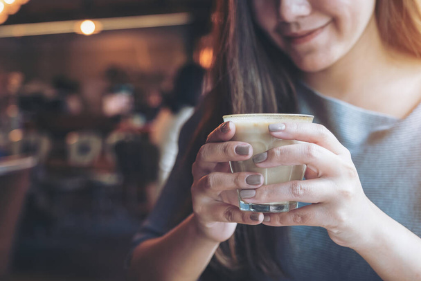 Close-up beeld van Aziatische vrouw houden en het drinken van hete koffie met een goed gevoel in cafe - Foto, afbeelding