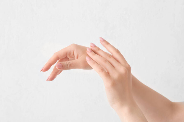 Hermosa joven aplicación de crema de manos contra fondo claro
 - Foto, imagen