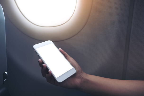 Bir uçağın yanında boş masaüstü ekranı olan beyaz bir telefonu tutan bir kadının el görüntüsü.  - Fotoğraf, Görsel