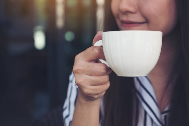 Closeup image of Asian woman smelling and drinking hot coffee with feeling good in cafe - Photo, Image