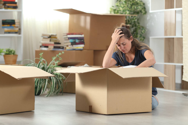 Sad evicted woman complaining moving out packing boxes sitting on the floor at home - Фото, изображение