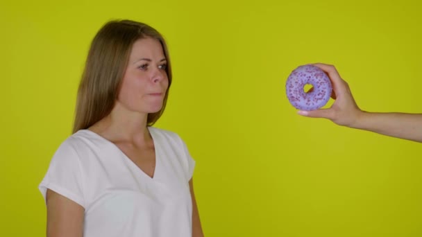 Πεινασμένη γυναίκα σε δίαιτα κοιτάζει το ντόνατ, γλείφει και δαγκώνει τα χείλη, θέλει να φάει - Πλάνα, βίντεο