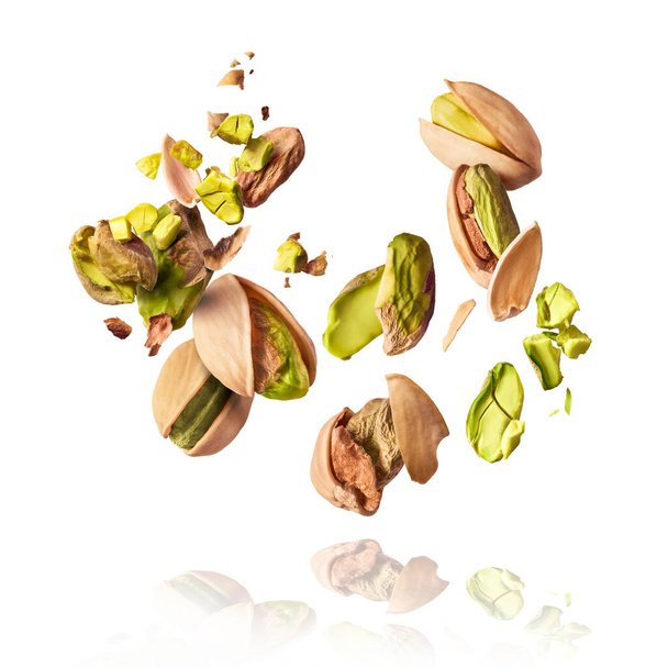 Flying in air fresh raw whole and cracked pistachios  isolated on white background. Concept of Pistachios is torn to pieces close-up. High resolution image - Photo, Image
