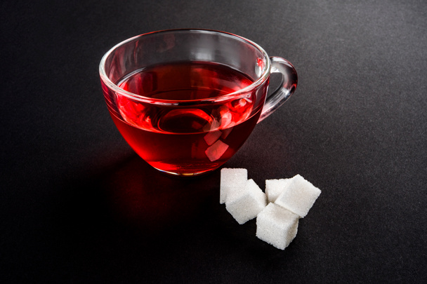 фруктовий чай у склянці біля цукрових кубиків на чорному фоні. ранковий напій
. - Фото, зображення