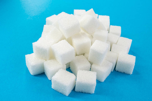 青の背景に砂糖のキューブ。糖尿病だ。スイーツ。厳格な食事 - 写真・画像