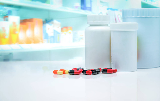 Capsule pills with drug bottles on white counter on blurred drug display shelf in pharmacy. Pharmacy shop background. Pharmaceutical industry. Health care and medicine concept. Prescription drugs. - Photo, Image