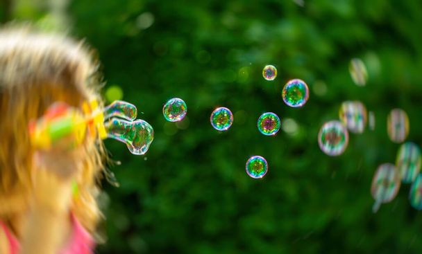 bubble. little girl blowing bubbles in the summer garden - Фото, изображение