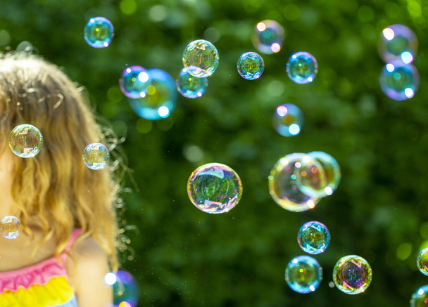 Bańka. mała dziewczynka dmuchanie pęcherzyki w letnim ogrodzie - Zdjęcie, obraz