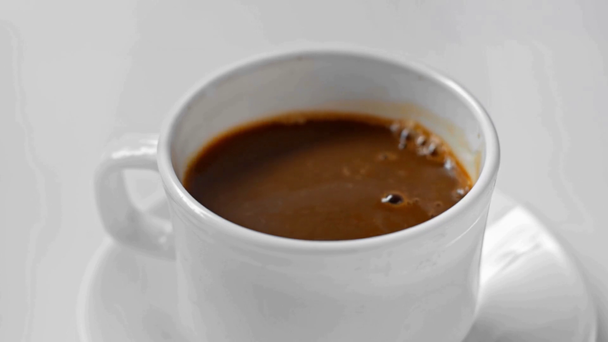 A fehér alapon izolált kávéba öntött cukorkockák lassú mozgása - Felvétel, videó