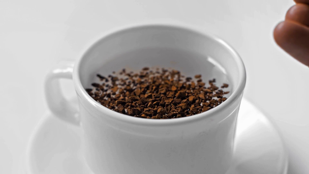 slow-motion van de mens gieten instant koffie in kopje met water geïsoleerd op wit - Video