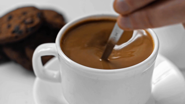Powolny ruch człowieka mieszającego smaczną kawę z łyżeczką na białym - Materiał filmowy, wideo