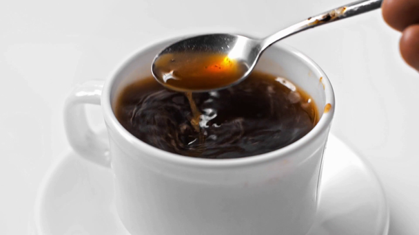 Mouvement lent de l'homme en remuant le café dans une tasse isolée sur blanc - Séquence, vidéo