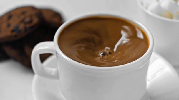 Powolny ruch człowieka mieszającego ciemną kawę w filiżance na białym - Materiał filmowy, wideo