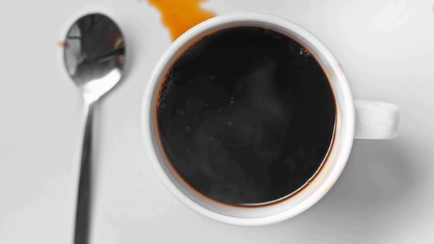 widok z góry kostki cukru spada do filiżanki czarnej kawy na białym  - Materiał filmowy, wideo