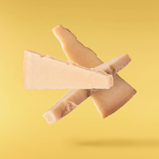 Tuore maukasta juustoa pudota ilmassa eristetty keltaisella pohjalla. Ruoka levitaatio käsite, laadukas kuva - Valokuva, kuva