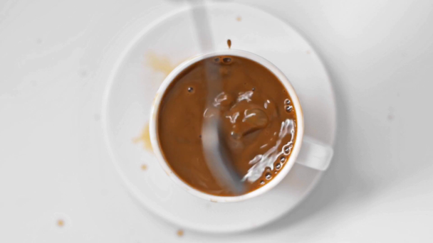 εστίαση έλξη του ανθρώπου κρατώντας κουτάλι κοντά καφέ στο κύπελλο στο λευκό  - Πλάνα, βίντεο